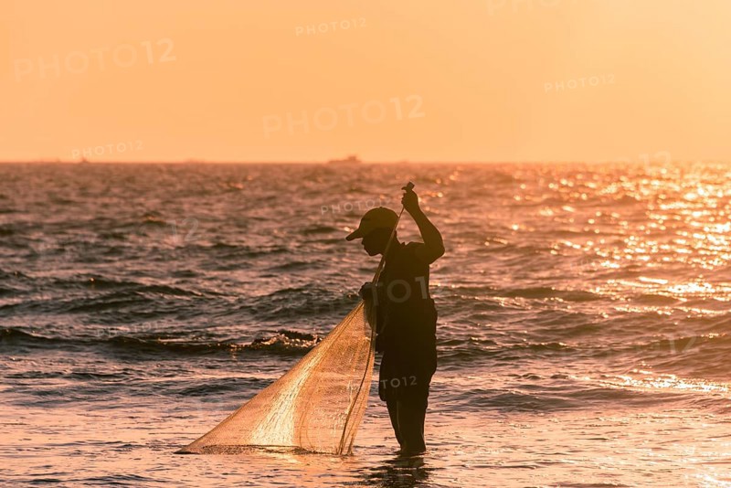 Local fishermen with fishing net in backlight