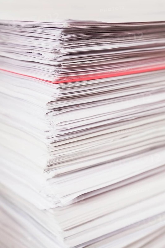 Pile of stacked white paper reports with red one sticking out