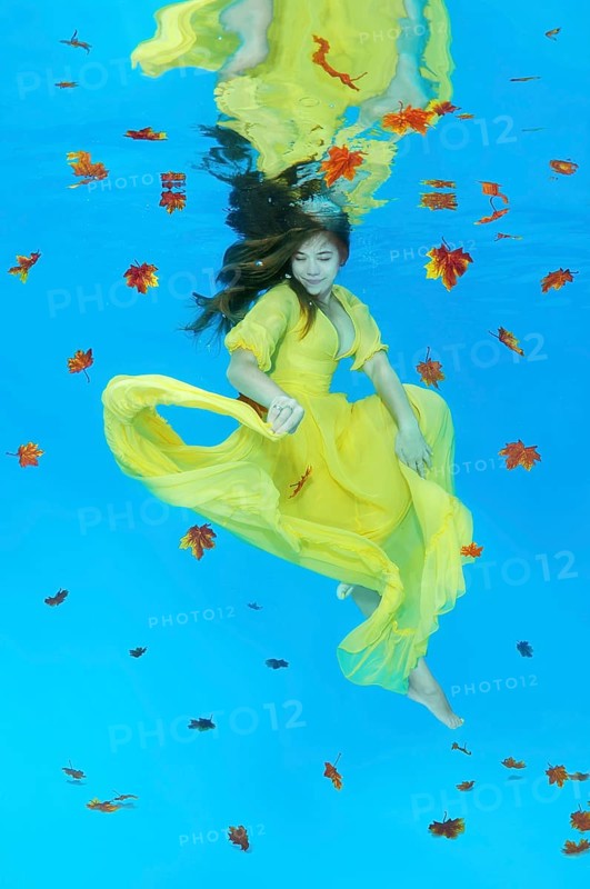Young woman in yellow dress posing under water