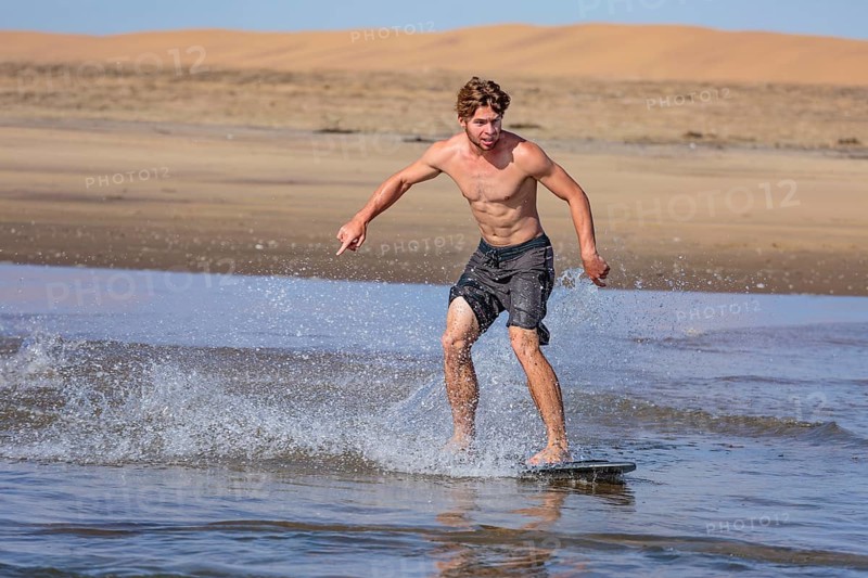 Young man skimboarding in the sea