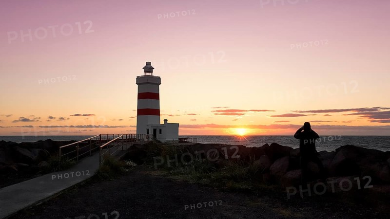 Man photographs sunset at lighthouse in Garour