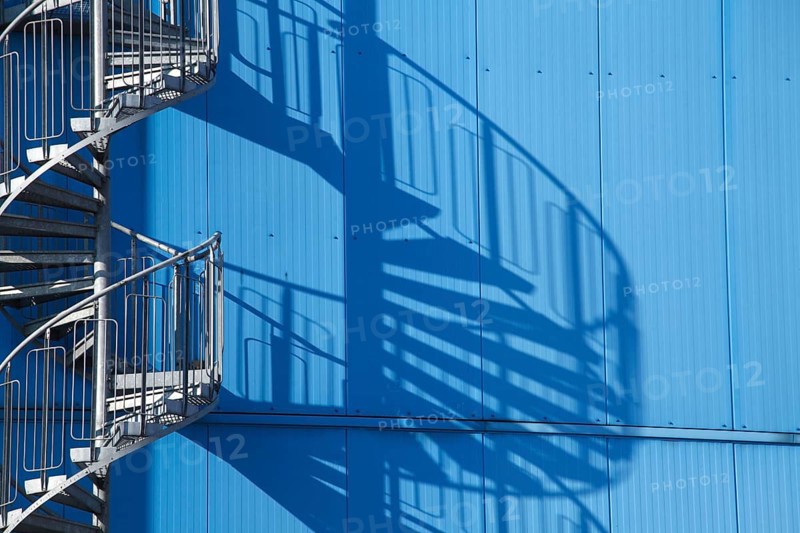 Spiral staircase and shadow on blue factory facade