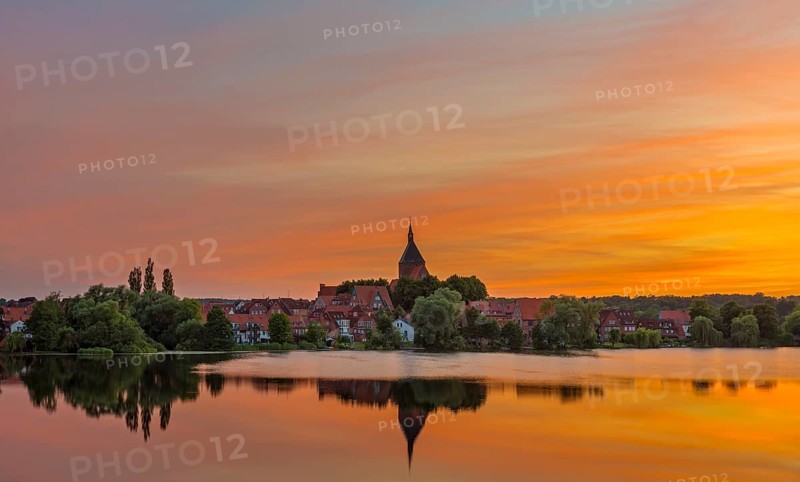 Cityscape with St. Nicholas' Church and lake Schulsee at sunset