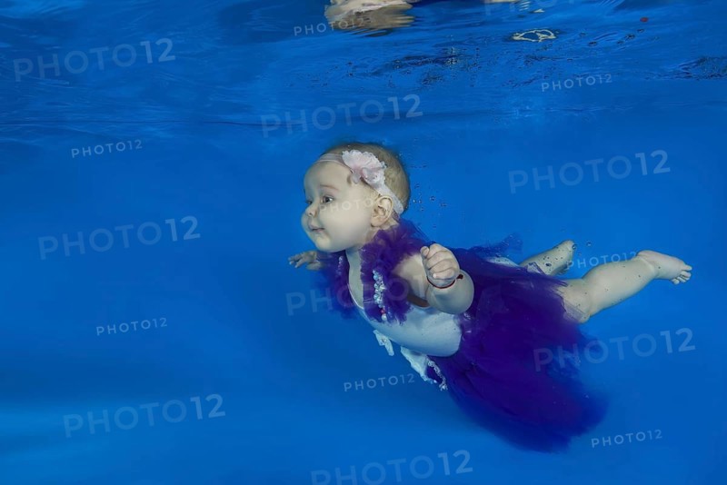Baby girl dressed as a ballet dancer swimming underwater in a pool