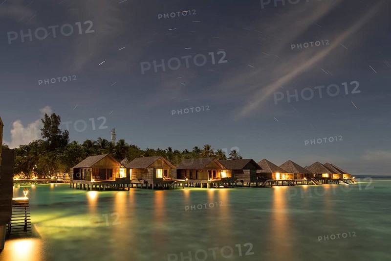 Wooden huts on stilts in lagoon at night