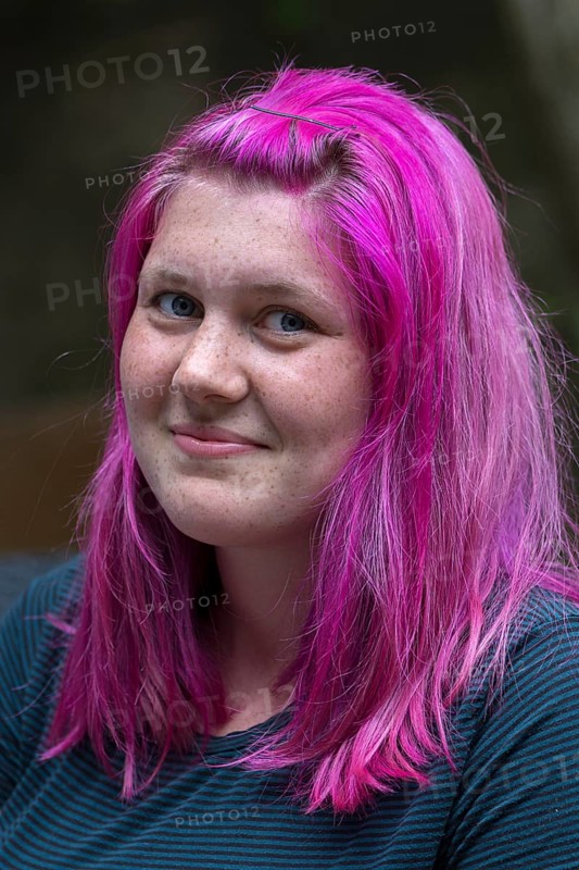 Portrait of a young woman with freckles and pink