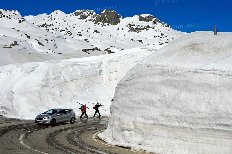 Car and two skiers in front of high snow walls