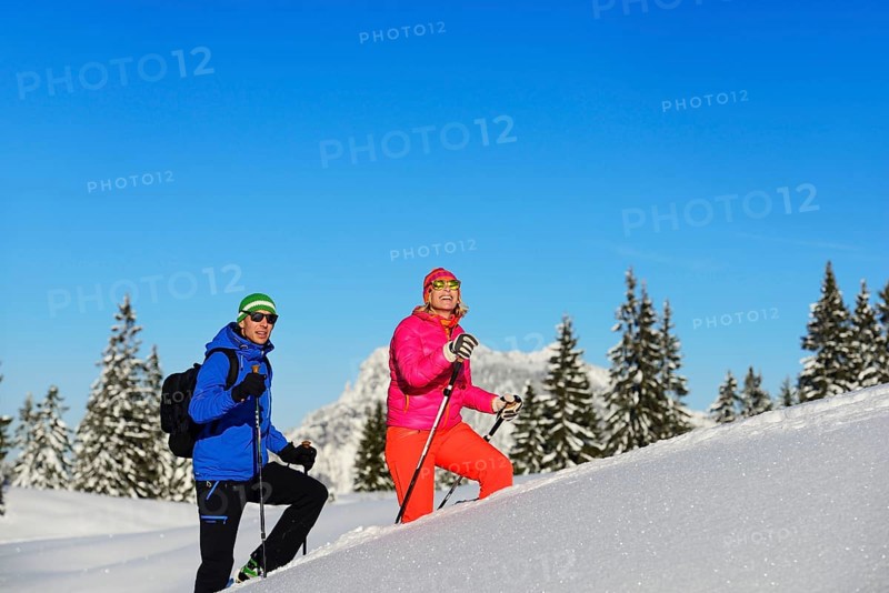 Two hikers walk through deep snow