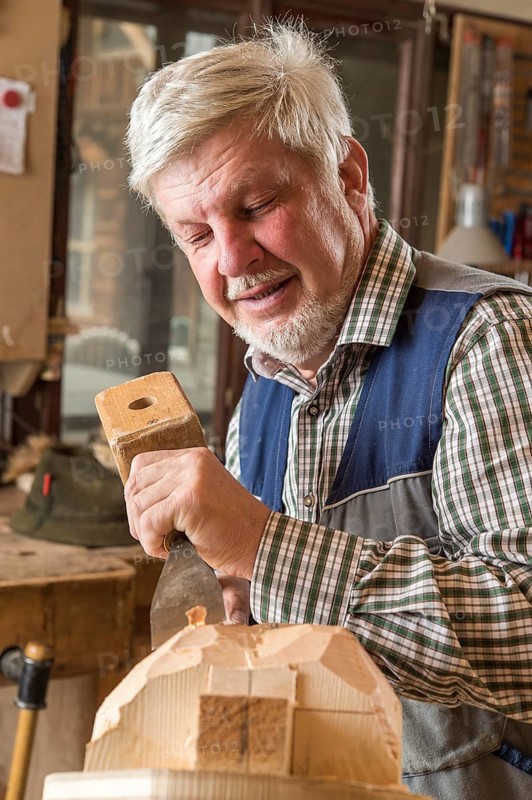 Wooden mask carver using wood carving tools on a wooden block