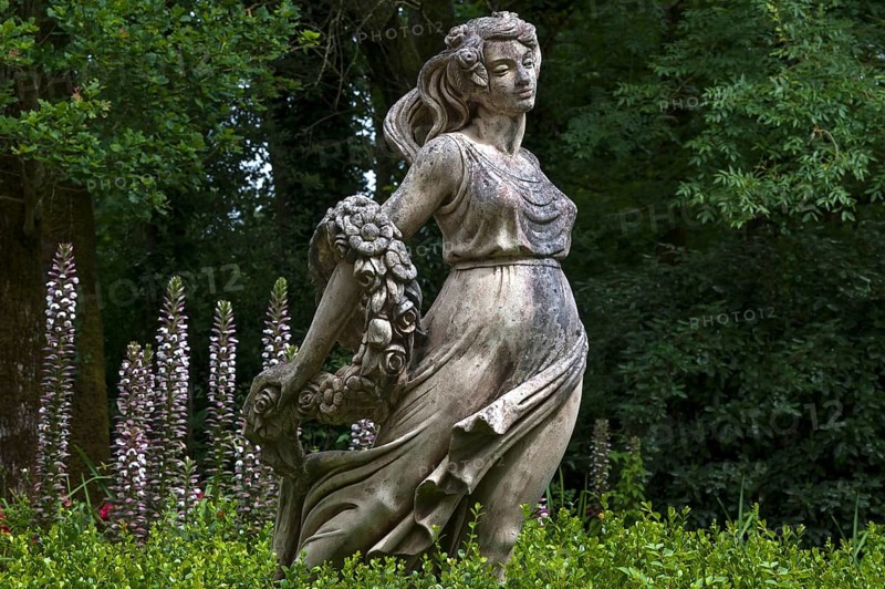 Female sculpture with a band of flowers behind acanthus