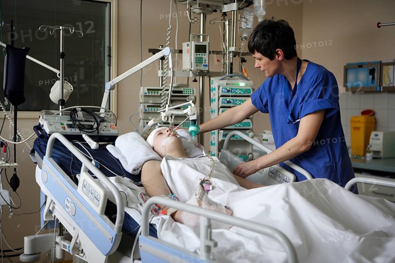 Child in hospital bed is attended by intensive care nurse