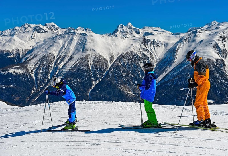 Three skiers against snowy Lepontine Alps