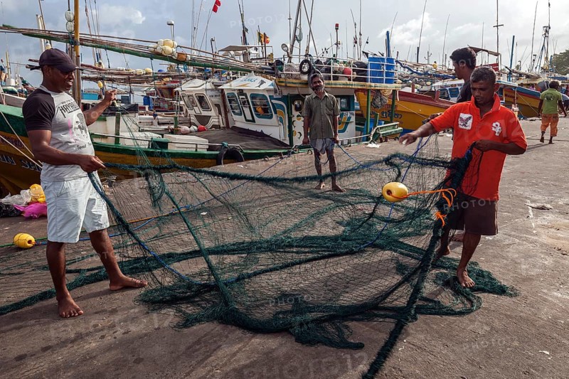 Local men untangling fishing nets in harbour