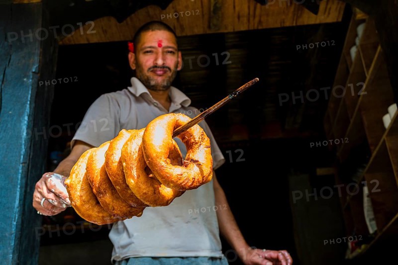 Salesman is displaying some fresh doughnuts on a wooden stick