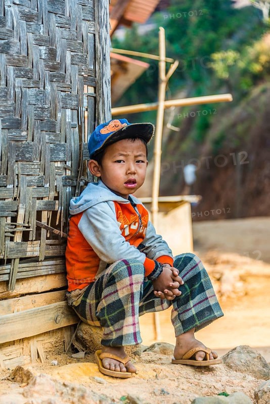 Little boy sitting in front of log cabin
