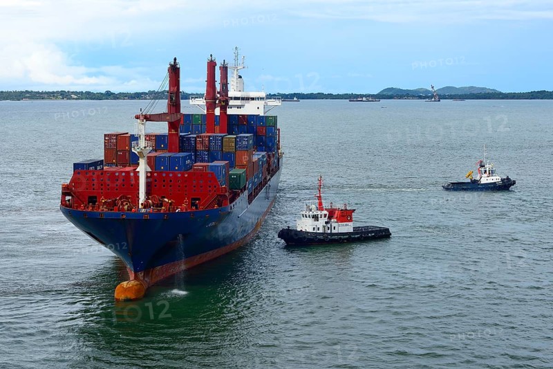 Container ship and pilot vessels berthing in the harbor