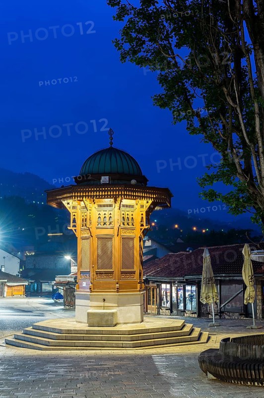 Illuminated Sebilj ottoman-style wooden fountain at sunrise