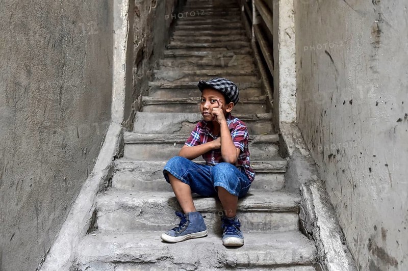 Boy on staircase with shirt and flat cap