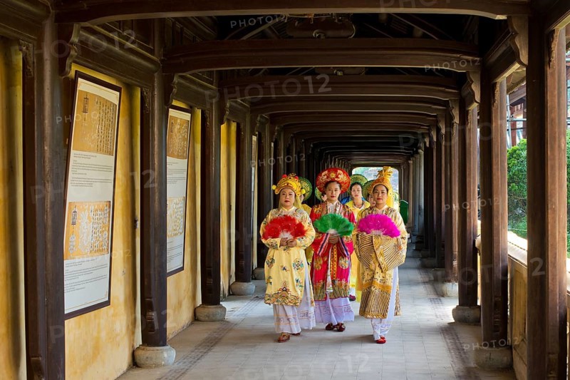 Vietnamese extras in traditional robes walking through imperial palace Hoang Thanh