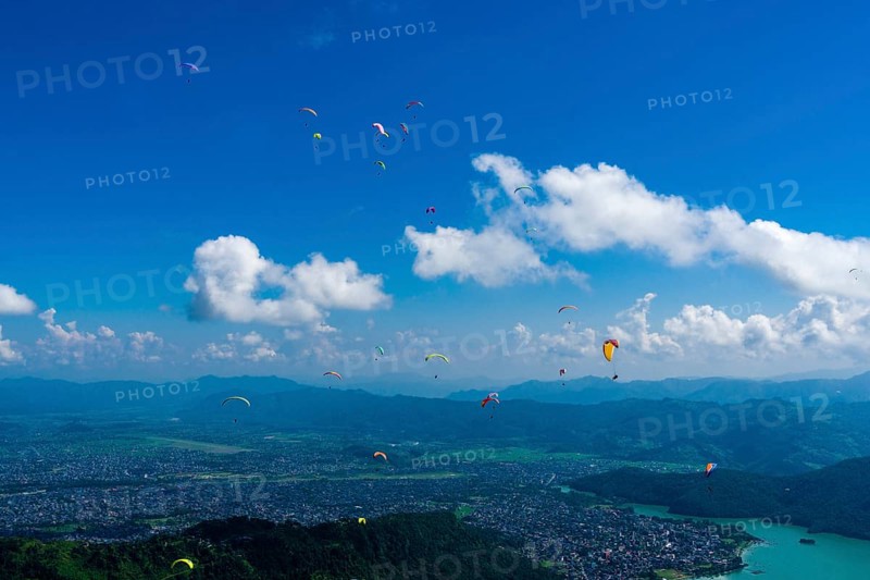 Many paragliders are flying over Pokhara and Phewa Lake
