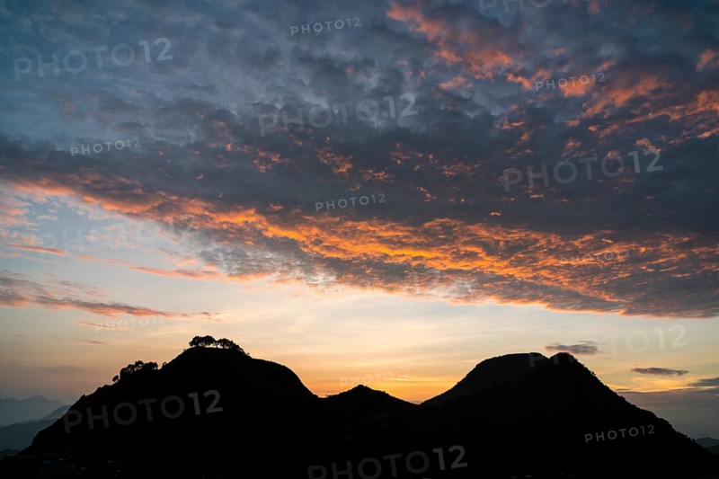 Red clouds over two hills at sunset