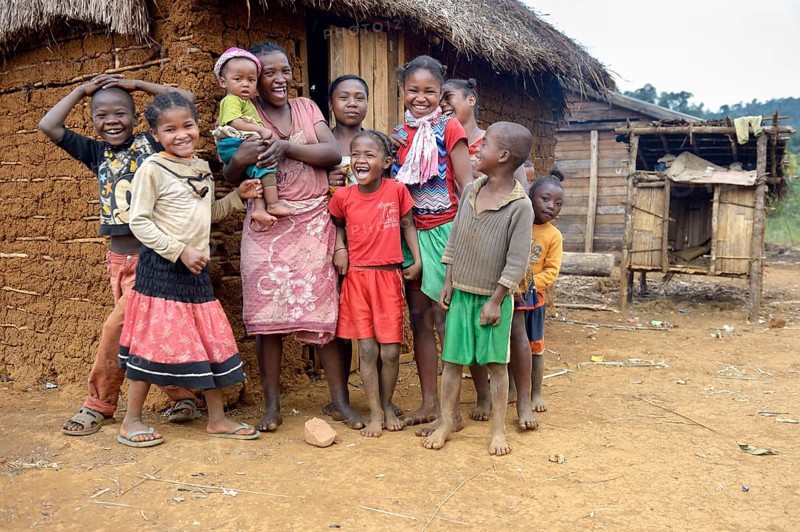 Laughing women and children in front of hut