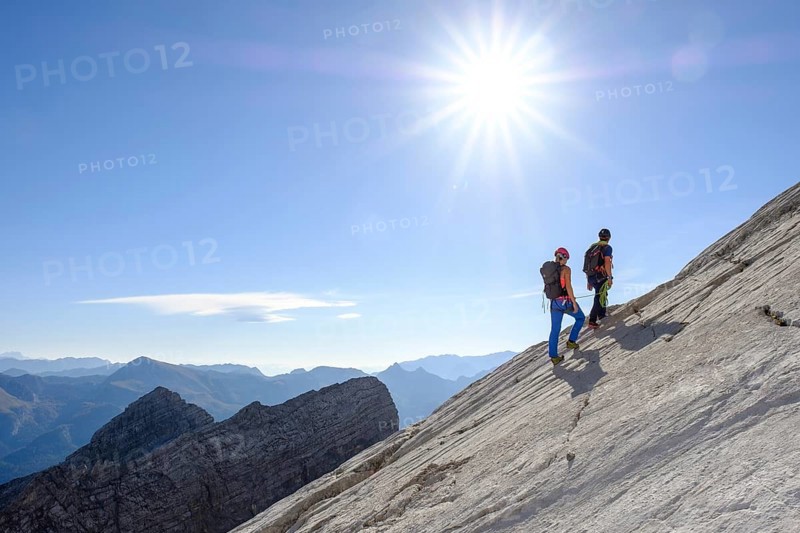 Mountain guide guiding a young woman on a short rope through a rock face
