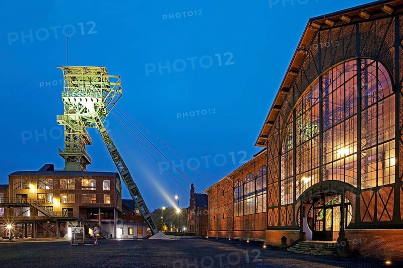 Illuminated machine hall with headframe at dusk