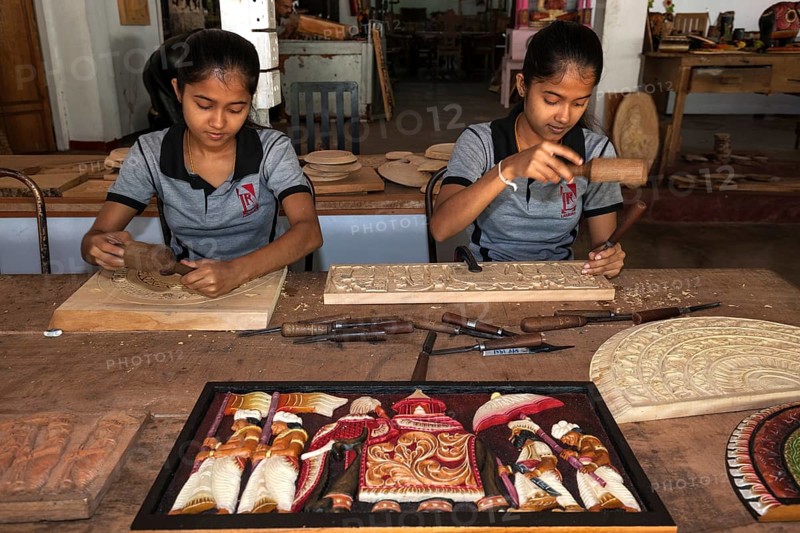 Native Sinhalese girls carving traditional wooden pictures