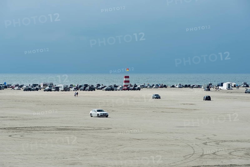 Cars parked on wide sandy beach