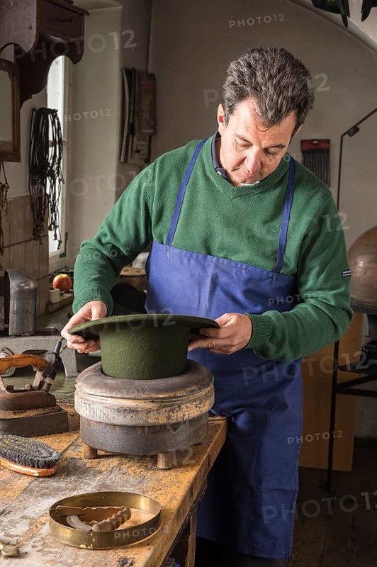 Hatter pushing dry wool felt hat into edge mold