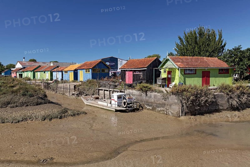 Colorful huts of oyster farmers on a channel at low tide