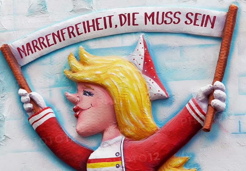 Papier mache figure holding carnival banner