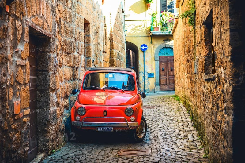 Old red Fiat 500 parked in a narrow alley
