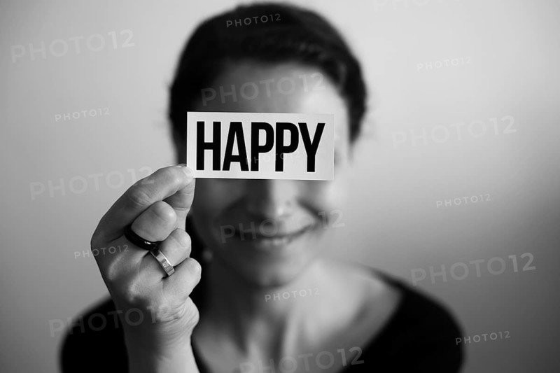 Portrait of a laughing woman holding a card with inscription Happy