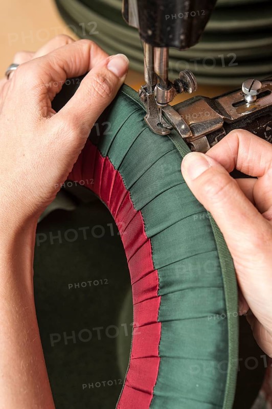 Hands sewing silk ribbon and inner lining on hat edge