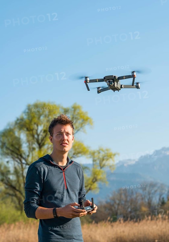 Young man controlling flying quadrocopter