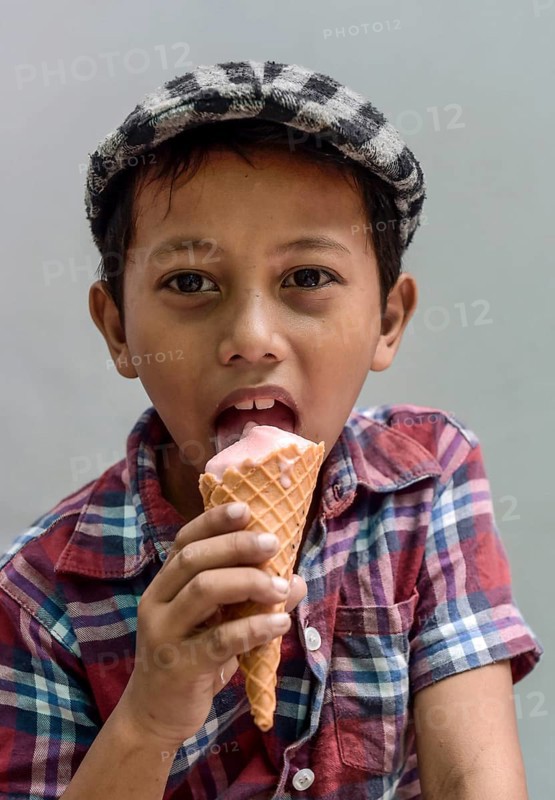 Boy with shirt and flat cap eating ice cream