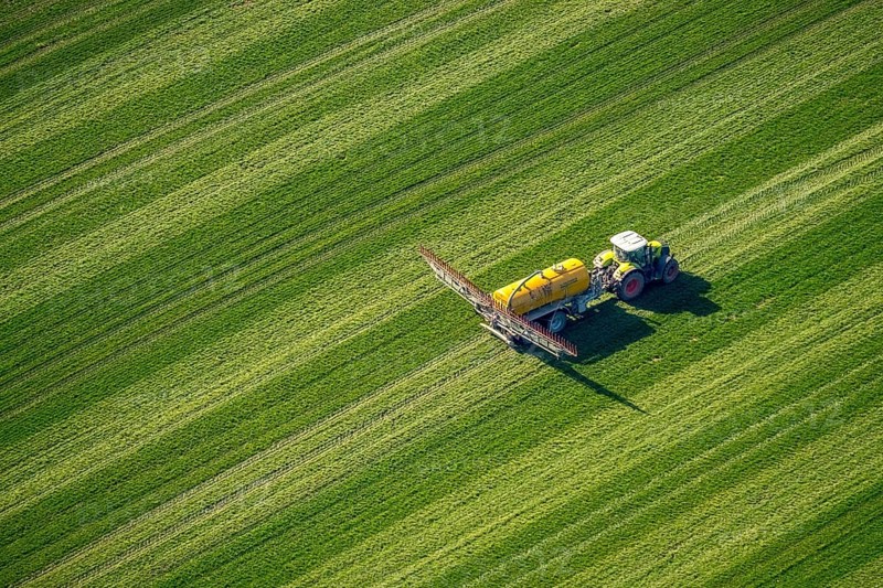 Tractor with pesticide sprayer on meadow