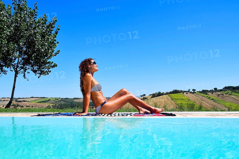 Woman sunbathing in bikini by a pool
