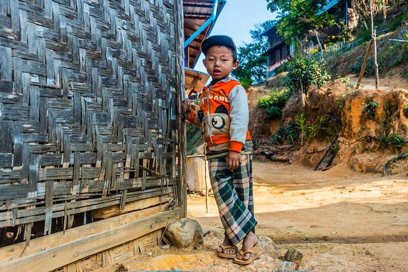 Little boy stands in front of log cabin
