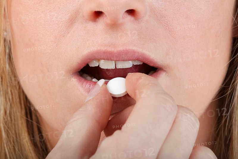 Close-up of young woman taking a pill