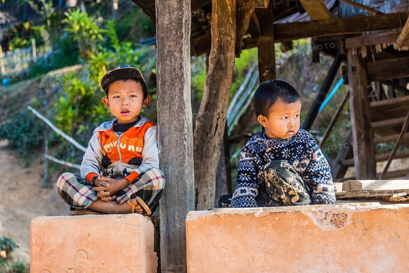 Two little boys sitting at log cabin