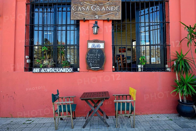 Table with chairs in front of a restaurant with red facade