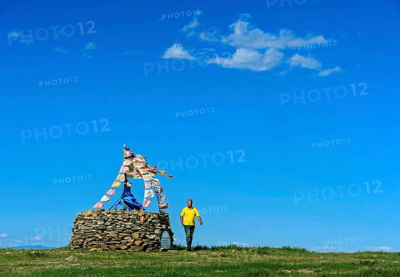 Mongolian man performing prayer ritual beside ovoo