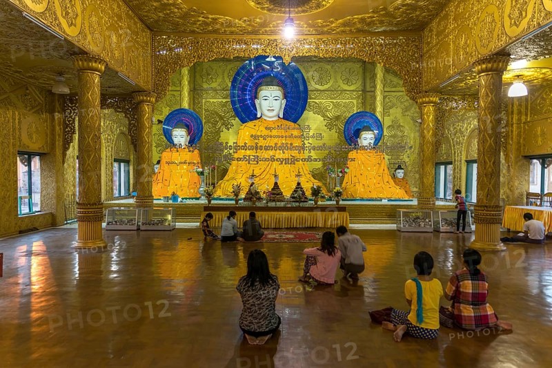 Religous people praying in front of Buddha statues Shwemokhtaw Pagoda