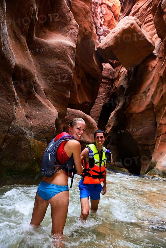 Young couple under big rock at the canyon of Wadi Mujib