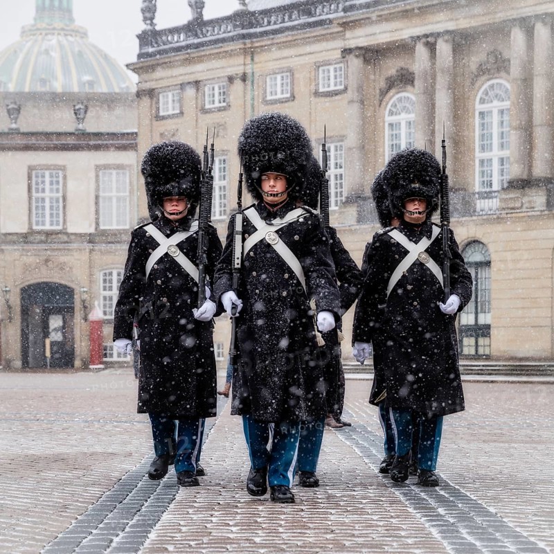 Royal Life Guards walking in front of Amalienborg Palace during snowy weather