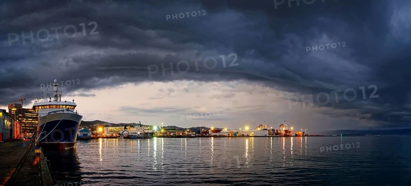 Harbour and Queens Wharf illuminated at sunset with dark storm clouds
