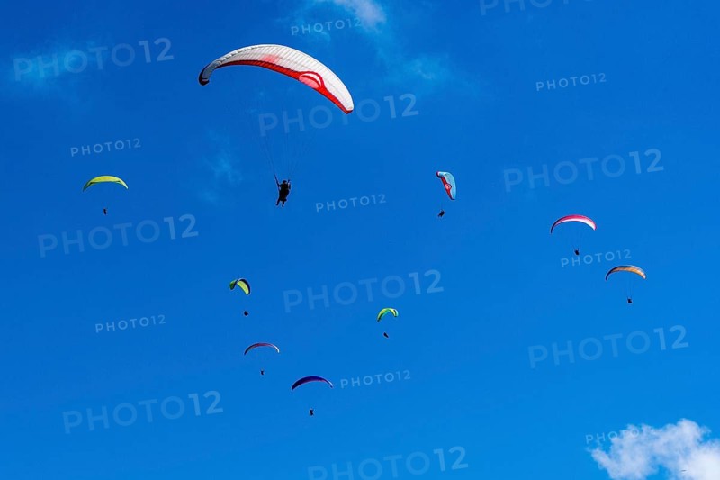 Many paragliders are flying in the air